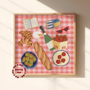 Könnte beinhalten: Ein gerahmtes Kreuzstichdesign mit Picknickartikeln auf einer rot-weiß karierten Decke. Enthält ein Baguette, Oliven, Erdbeeren, Croissants, Käse, Sonnenbrille und eine Champagnerflasche. Der Text "140 x 140 DIGITAL PDF" ist unten links.