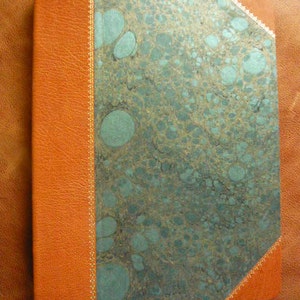 Puede incluir: Un diario encuadernado en cuero marr&oacute;n con una cubierta de m&aacute;rmol turquesa. La cubierta tiene un borde dorado decorativo.
