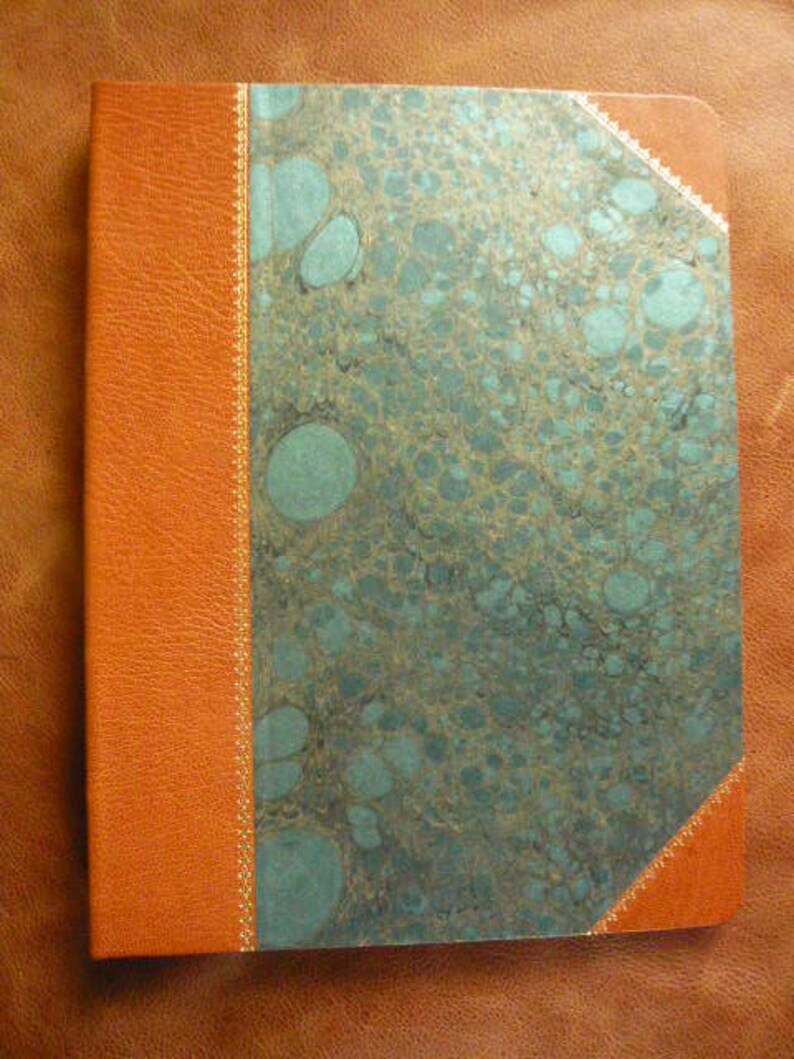 Puede incluir: Un diario encuadernado en cuero marr&oacute;n con una cubierta de m&aacute;rmol turquesa. La cubierta tiene un borde dorado decorativo.