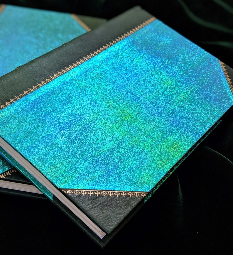 May include: A teal blue hardcover book with a gold decorative border. The book has a textured, iridescent cover.