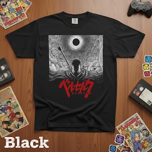 May include: Black t-shirt featuring a detailed black and white graphic of a warrior with a large sword, a dark sun, and the word "BERSERK" in red. The shirt is made of a soft material.