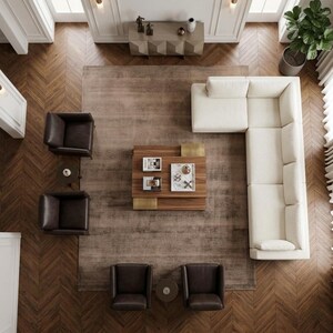 Pode incluir: Vista a&eacute;rea de uma sala de estar moderna com um sof&aacute; seccional creme, quatro poltronas de couro marrom e uma mesa de centro de madeira com detalhes em lat&atilde;o. Um tapete grande e piso de madeira completam o espa&ccedil;o.