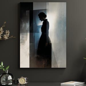 May include: An abstract art print featuring a silhouette of a person in a long black dress. The artwork uses a palette of black, white, and blue, with geometric shapes and a soft, diffused light effect. The print is displayed on a dark gray wall.