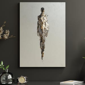 May include: Abstract art print depicting a human form. The artwork has a textured, layered appearance with silver, gold, and brown tones against a neutral backdrop. The figure is centrally positioned on a rectangular canvas, offering a contemporary feel.