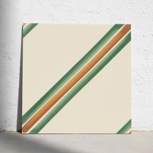 May include: A square ceramic tile with an off-white base colour featuring a diagonal pattern of two parallel dark green stripes flanking a central orange stripe that runs from the upper right corner to the lower left corner of the tile surface.