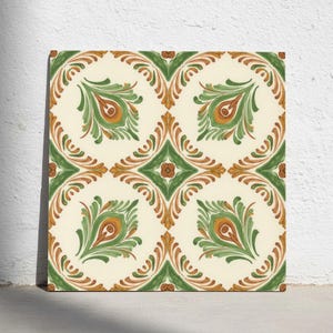 Può includere: Una piastrella quadrata in ceramica con un motivo ripetitivo di foglie stilizzate verdi e arancioni su sfondo color crema. Il design è composto da elementi curvi e simmetrici disposti in una griglia, creando una decorazione floreale.