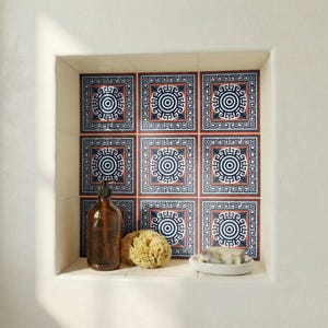 Peut inclure: Étagère encastrée avec des carreaux décoratifs à motif circulaire bleu et blanc et bordure géométrique. Une bouteille en verre marron, une éponge naturelle et un porte-savon blanc avec du savon sont sur l'étagère.
