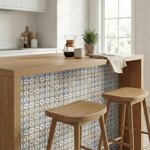 May include: A kitchen island with a wooden countertop and a decorative tile backsplash featuring nautical symbols. Two wooden stools are in front of the island. A coffee maker, mug, and potted plant are on the countertop. The color scheme is neutral with blue and brown accents.