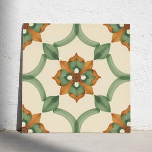 Op de afbeelding: Een vierkante keramische tegel met een herhalend bloemmotief in saliegroen en gebrand oranje op een crèmekleurige achtergrond. Het ontwerp bestaat uit een centraal gestileerd bloemmotief omringd door gebogen groene lijnen en hoekaccenten.