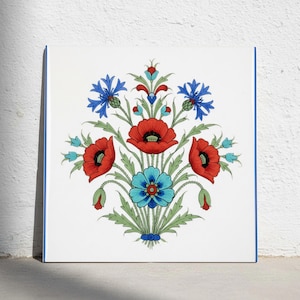 May include: A square white tile featuring a centered botanical illustration of red poppies, blue cornflowers, and light blue blossoms with green stems and leaves. The design is symmetrical, showcasing vibrant floral colors on a clean white background.