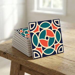 Könnte beinhalten: Ein Stapel quadratischer Keramikuntersetzer mit geometrischem Design. Die Untersetzer haben einen marineblauen Hintergrund mit teal-, orange- und cremefarbenen kreisförmigen und halbkreisförmigen Formen. Die Untersetzer sind auf einer Holzoberfläche gestapelt.