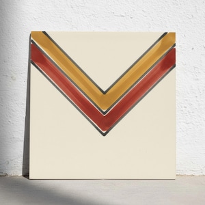 May include: A square ceramic tile with a cream-coloured base featuring a geometric chevron pattern. The design consists of two nested V-shaped stripes in mustard yellow and deep red, each outlined with thin, dark charcoal grey lines.