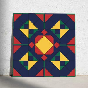 May include: A square canvas print featuring a geometric pattern. The design includes a central yellow diamond shape, surrounded by red and green squares and triangles, set against a navy blue background. The edges are outlined in red and green.