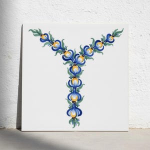 May include: A square white tile featuring a hand-painted letter Y formed by a series of blue, yellow, and green floral motifs. The design consists of stylized petals and leaves arranged in a vertical and diagonal pattern centered on the tile.