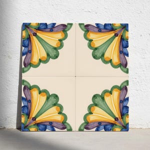 May include: A set of four square ceramic tiles arranged in a grid, each featuring a cream-coloured background with a hand-painted floral corner motif in vibrant shades of yellow, green, blue, and purple, creating a symmetrical pattern when joined.