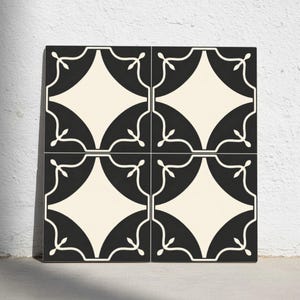 Puede incluir: Cuatro baldosas cuadradas dispuestas juntas, con un patrón repetitivo. Cada baldosa tiene una combinación de colores negro y crema. El diseño incluye una forma de diamante en el centro, rodeada por un semicírculo negro y líneas blancas decorativas.