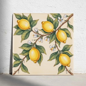 Puede incluir: Un azulejo de cerámica cuadrado con una ilustración botánica pintada a mano de una rama de limonero. El diseño muestra cinco limones de color amarillo brillante, hojas de color verde oscuro y pequeñas flores blancas sobre un fondo crema.
