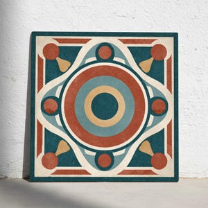Puede incluir: Azulejo cuadrado con un diseño geométrico que presenta círculos concéntricos en tonos de rojo, verde azulado y azul, con detalles en crema y dorado. El azulejo tiene un aspecto texturizado y está colocado contra una pared blanca.