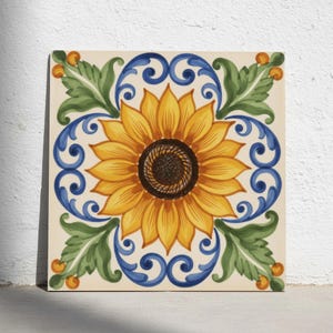 Könnte beinhalten: Eine quadratische Keramikfliese mit einer zentralen gelben Sonnenblume mit dunkelbrauner Mitte. Das Design ist von symmetrischen blauen Schnörkeln und grünen Akanthusblättern umrahmt, akzentuiert durch kleine orangefarbene Kreismotive auf cremefarbenem Grund.