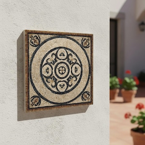 Puede incluir: Obra de arte de mosaico cuadrado con un diseño circular. El mosaico presenta un fondo beige con un patrón circular negro y marrón oscuro. El borde es de color marrón oscuro. La obra de arte está montada en una pared blanca.