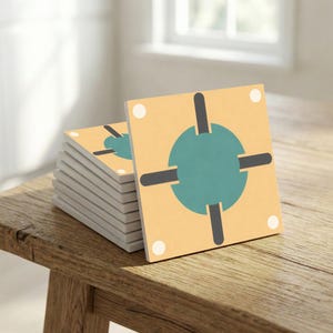 May include: A stack of square coasters with a geometric design. Each coaster has a light yellow background with a teal circle and black cross-like shapes. White dots are in each corner. The coasters are stacked on a wooden surface.