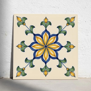 Könnte beinhalten: Eine quadratische Keramikfliese mit cremefarbenem Hintergrund und einem zentralen gelb-blauen Blumenmotiv. Das Design enthält symmetrische, blattartige Akzente in Grün und Gelb, die zu den Ecken hin verlaufen und ein ausgewogenes Muster bilden.