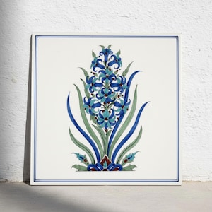 May include: A square ceramic tile featuring a central hand-painted floral motif of a blue hyacinth with green leaves. The design includes dark blue, light blue, and green tones with small red accents at the base, all framed by a thin blue border.
