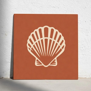 Puede incluir: Una impresión artística cuadrada de color terracota con una ilustración de concha marina de color crema. La concha marina está centrada y tiene un diseño detallado en forma de abanico. El fondo es de un tono sólido, cálido y terroso.