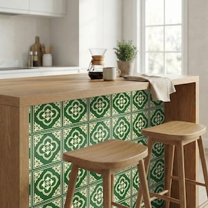 Puede incluir: Isla de cocina de madera con azulejos estampados verdes y crema. Dos taburetes de madera frente a la isla. Una cafetera, una taza y una planta en maceta están en la superficie. La cocina tiene un ambiente luminoso y aireado.