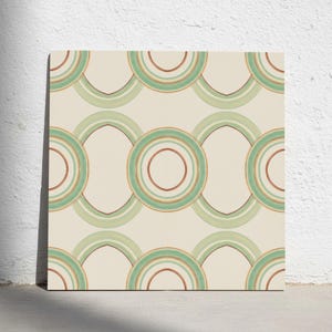 Puede incluir: Un azulejo cuadrado con un patrón geométrico repetitivo de círculos y óvalos concéntricos en tonos verde salvia, menta claro y marrón terracota sobre un fondo de color crema sólido, creando un diseño equilibrado y simétrico.