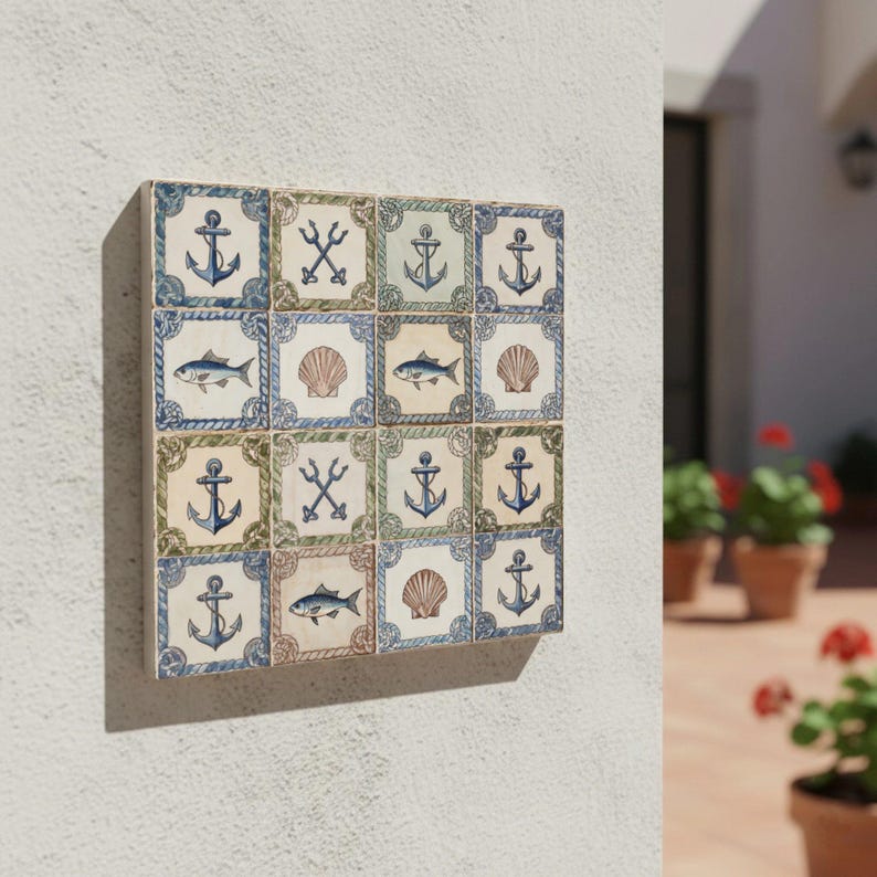 May include: A square wall art piece composed of sixteen ceramic tiles. Each tile features nautical designs such as anchors, fish, seashells, and tridents. The tiles are in shades of blue, green, and beige, with a decorative border.