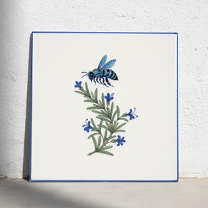 May include: A square white ceramic tile with a thin blue border featuring a detailed illustration of a blue bee hovering above a green sprig of rosemary with small blue flowers. The design is centered on the tile, showcasing clear lines.