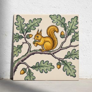 May include: A square decorative tile featuring a detailed illustration of a golden-brown squirrel perched on an oak branch. The squirrel holds an acorn, surrounded by green oak leaves and several hanging acorns against a cream-colored background.