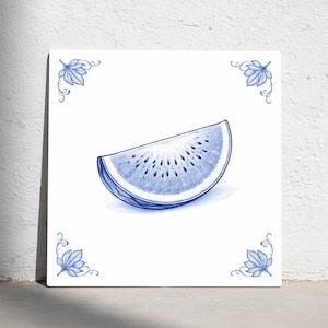 Peut inclure: Carreau blanc carré avec une illustration bleue d'une tranche de kiwi. La tranche de kiwi est détaillée et entourée de motifs de feuilles bleues dans les coins. L'œuvre est de style aquarelle.