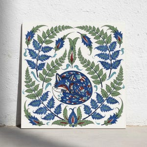Könnte beinhalten: Eine quadratische Keramikfliese mit einer zentralen Illustration eines zusammengerollten Fuchses in Blau-, Weiß- und Rottönen. Der Fuchs ist von einem symmetrischen Rahmen aus grünen farnartigen Blättern und blauen Blumenmotiven umgeben.