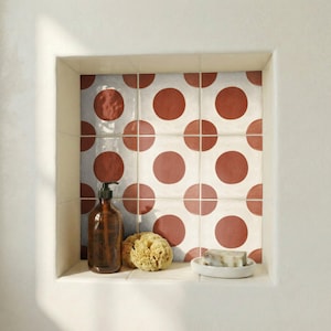 May include: A bathroom niche with a patterned tile backsplash featuring large, rust-colored polka dots on a white background. A brown glass bottle with a pump, a natural sponge, and a bar of soap on a white dish are visible.
