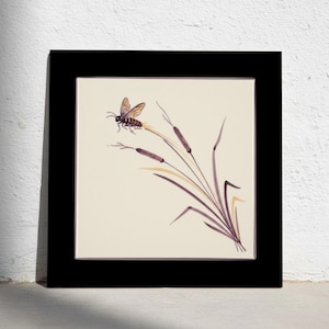 May include: A square wall art piece featuring a black frame surrounding a cream-colored center panel. The artwork depicts a detailed illustration of a winged insect perched on a cluster of slender, dark purple cattail stalks with pale yellow leaves.