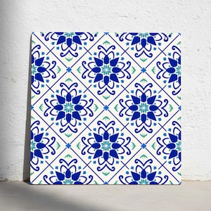 Puede incluir: Azulejo decorativo cuadrado con un patrón floral repetitivo en tonos azules y verdes sobre un fondo crema. El diseño presenta flores estilizadas y formas geométricas, creando un aspecto simétrico y ornamentado.