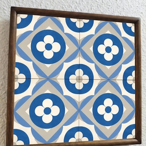 Puede incluir: Un conjunto cuadrado de baldosas decorativas con un patrón repetitivo de diseños florales azules, blancos y grises. Las baldosas están enmarcadas en un marco de madera marrón oscuro, creando un aspecto cohesivo y elegante.