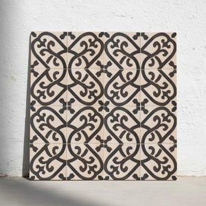 Puede incluir: Una disposición cuadrada de dieciséis baldosas decorativas. Cada baldosa presenta un fondo color crema con un patrón negro, adornado y arremolinado. Las baldosas están dispuestas en una cuadrícula, creando un diseño cohesivo adecuado para pisos o paredes.
