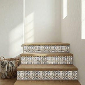 May include: Wooden staircase with decorative tiles featuring nautical symbols. The tiles have a blue, white, and tan color scheme. The steps are made of light brown wood. A woven basket with a blanket is in the corner.