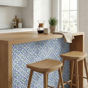 May include: A kitchen island with a wooden countertop and a decorative tile backsplash. The tile features a repeating pattern of blue, green, and gold floral designs. Two wooden stools are in front of the island.