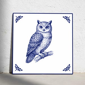 May include: Square ceramic tile featuring a detailed blue and white illustration of an owl perched on a branch. The owl is depicted with intricate feather details. Decorative leaf accents are in each corner.