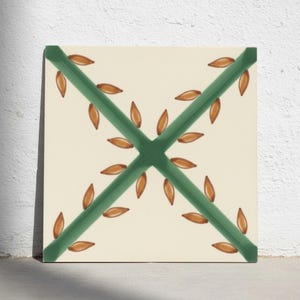 Puede incluir: Un azulejo de cerámica cuadrado con fondo blanco roto que presenta dos líneas diagonales de color verde oscuro que se cruzan formando una X. Pequeños motivos de hojas marrones en forma de almendra se disponen a lo largo de cada línea.