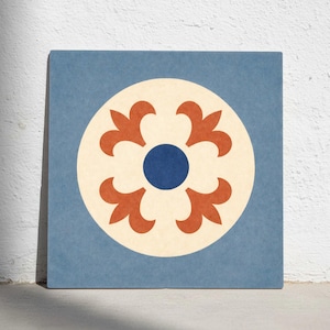 Può includere: Piastrella quadrata blu con un disegno centrale. Il disegno presenta un cerchio color crema con un motivo floreale color ruggine e un centro blu. La piastrella è probabilmente per l'arredamento della casa o simili.