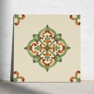 Può includere: Una piastrella in ceramica quadrata con sfondo color crema caratterizzata da un motivo floreale centrale simmetrico nei toni del verde salvia e dell'arancione bruciato. Il design include quattro accenti angolari abbinati.