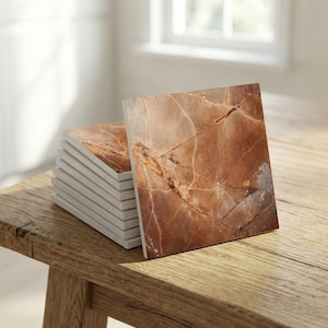 Peut inclure: Une pile de dessous de verre carrés avec un motif de marbre dans les tons bruns et beiges. Les dessous de verre ont une finition brillante et des bords blancs. Ils sont disposés sur une surface en bois, éclairés par la lumière naturelle.