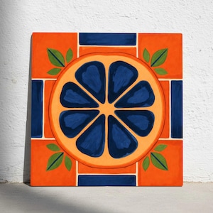 May include: Square orange canvas art featuring a stylized orange slice design. The orange slice is a vibrant mix of orange and deep blue, surrounded by a geometric pattern in the same colors. Green leaves add a natural touch.