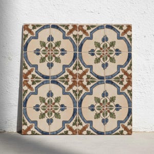 Könnte beinhalten: Quadratische dekorative Fliesen mit einem sich wiederholenden Muster. Jede Fliese hat einen cremefarbenen Hintergrund mit einem blauen Rand, braunen und grünen floralen Akzenten. Die Fliesen sind in einem Raster angeordnet.