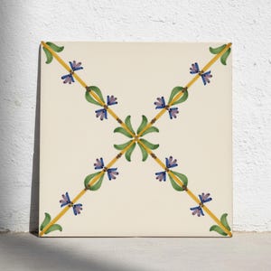 Puede incluir: Un azulejo de cerámica cuadrado con base de color blanco roto que presenta un patrón de cruz central. El diseño consiste en finas líneas diagonales amarillas acentuadas con hojas verdes y pequeños grupos de flores moradas dispuestas simétricamente.